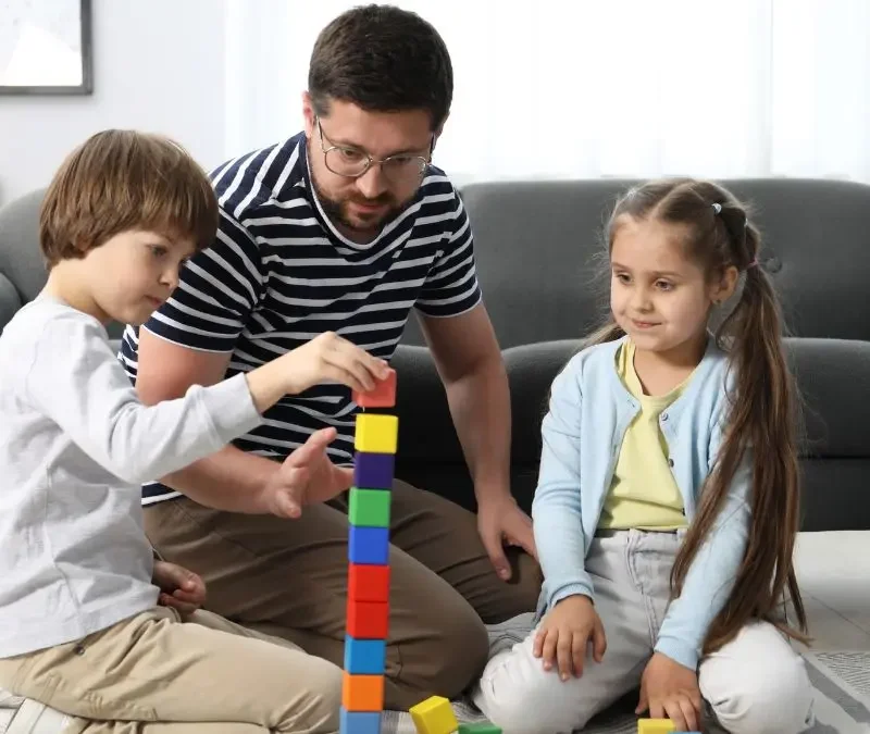 father-and-children-building-colorful-block-tower-together-at-home