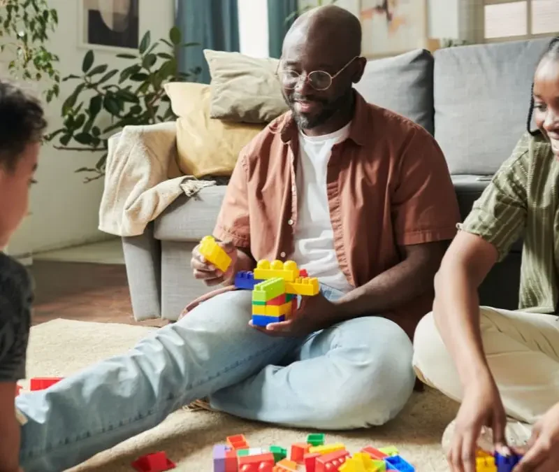 parents-and-child-playing-with-building-blocks-on-living-room-floor
