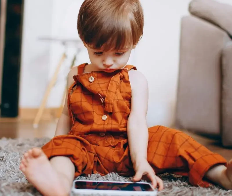 toddler-sitting-on-rug-using-mobile-device-at-home