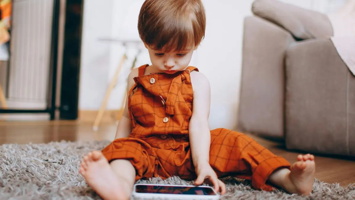 toddler-sitting-on-rug-using-mobile-device-at-home
