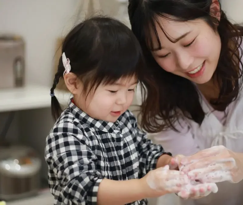 child-and-woman-smiling-while-washing-hands-together