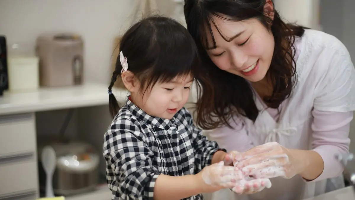 child-and-woman-smiling-while-washing-hands-together