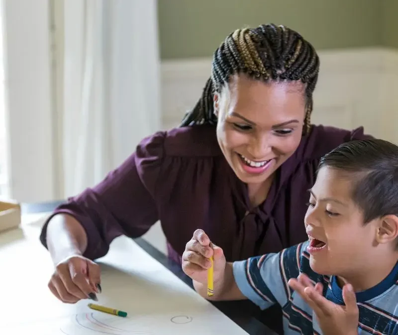 child-holding-crayon-with-woman-during-table-activity