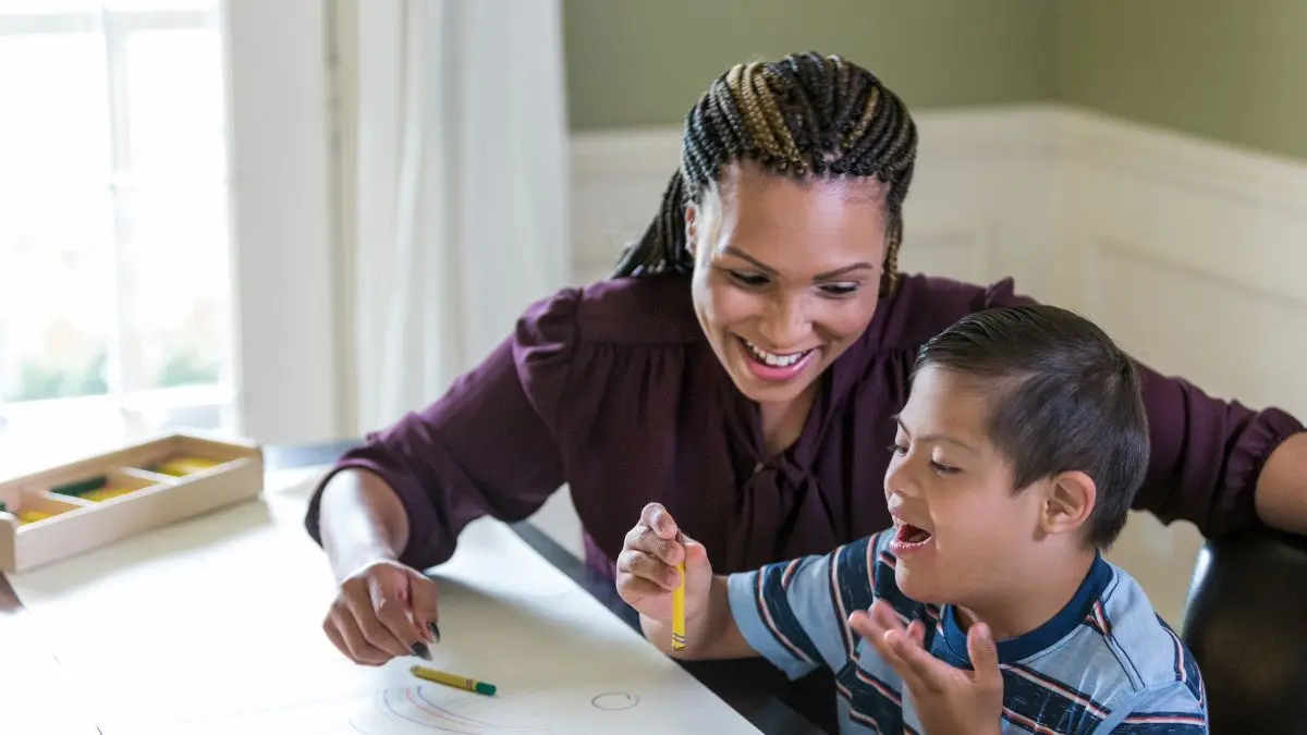 child-holding-crayon-with-woman-during-table-activity