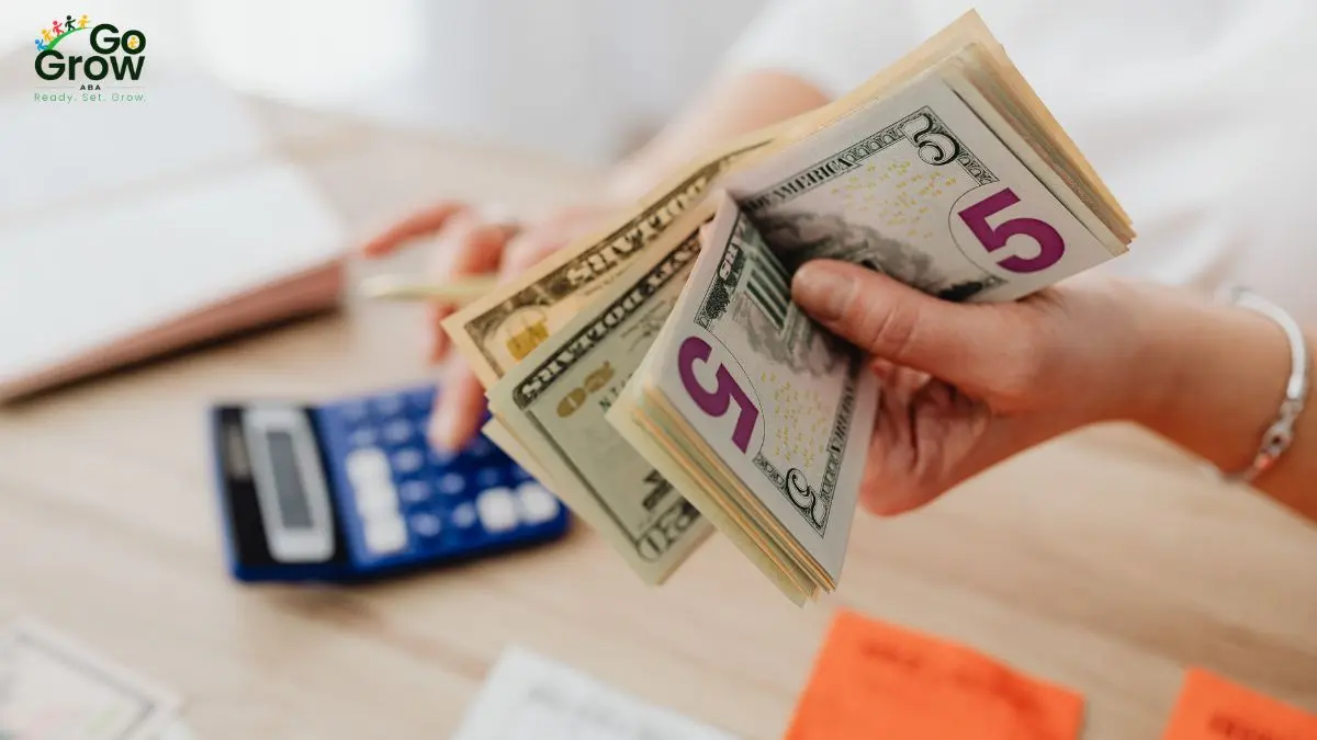 hand-holding-us-dollar-bills-near-calculator