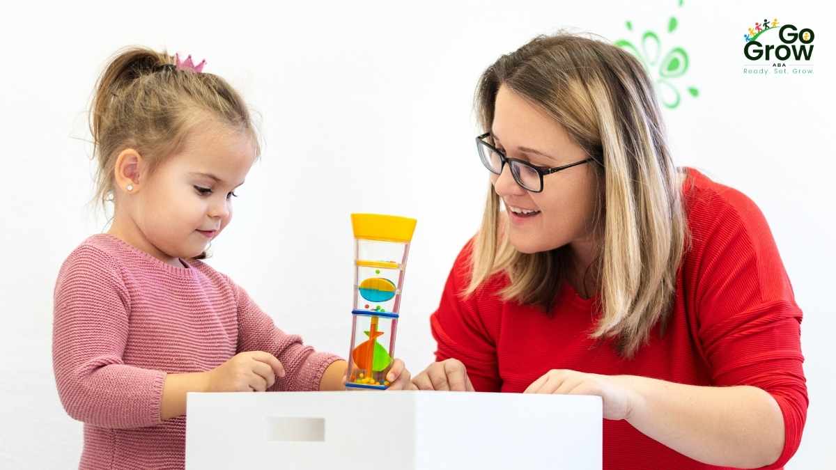 ABA therapist and young girl exploring a colorful sensory toy together during a session
