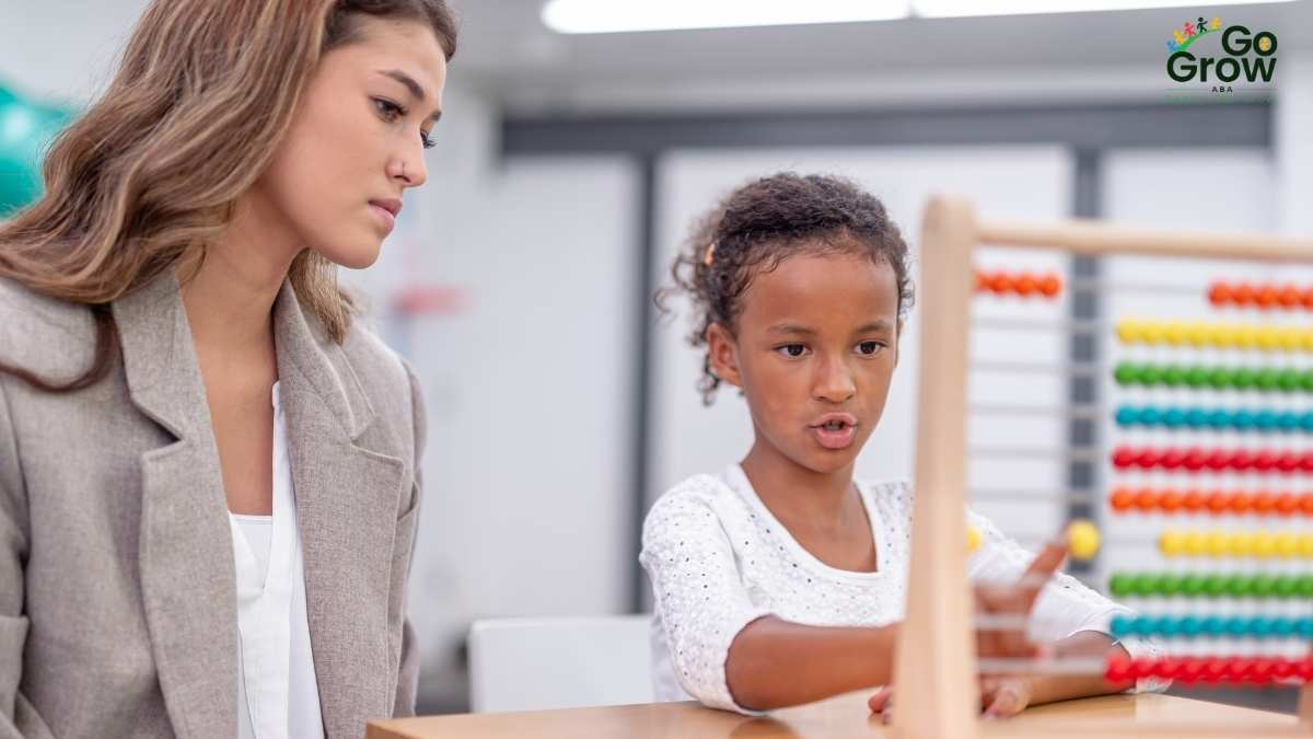 Therapist observing a focused young girl using an abacus during a therapy session