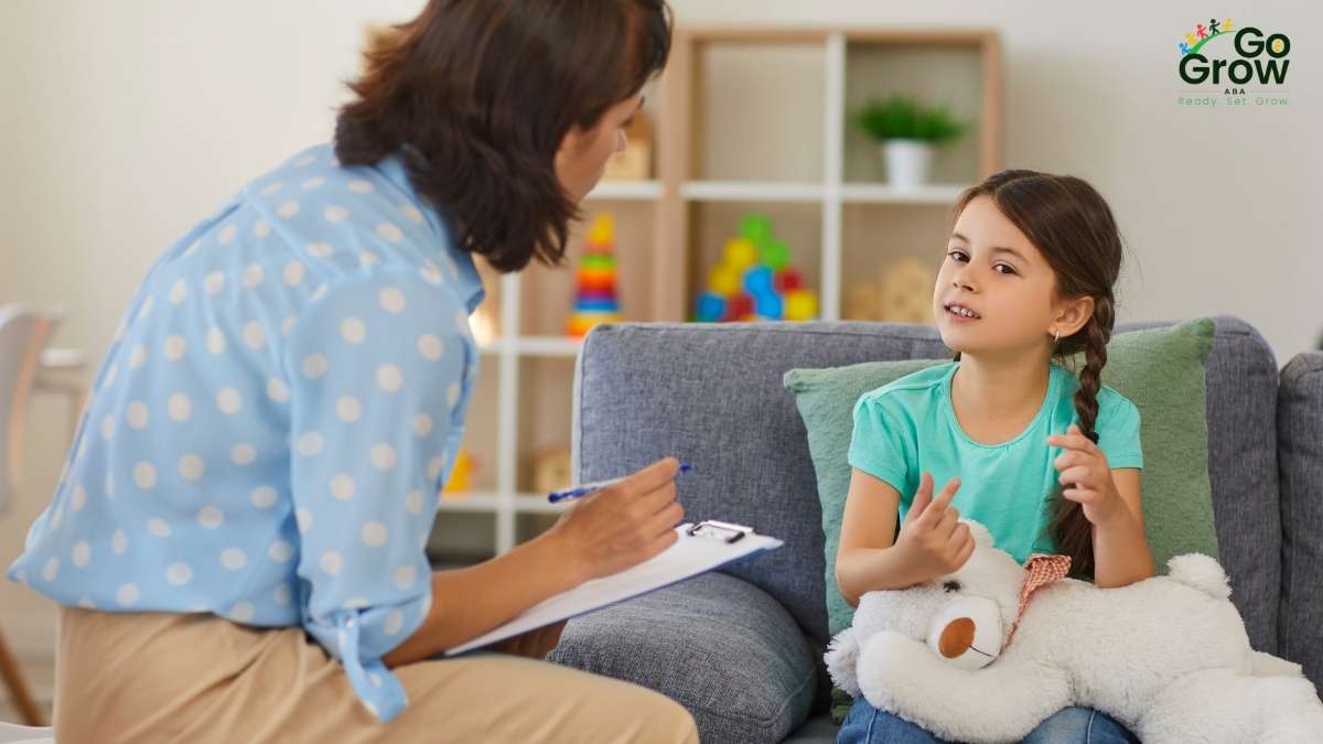Therapist taking notes while a young girl talks during an in-home therapy session