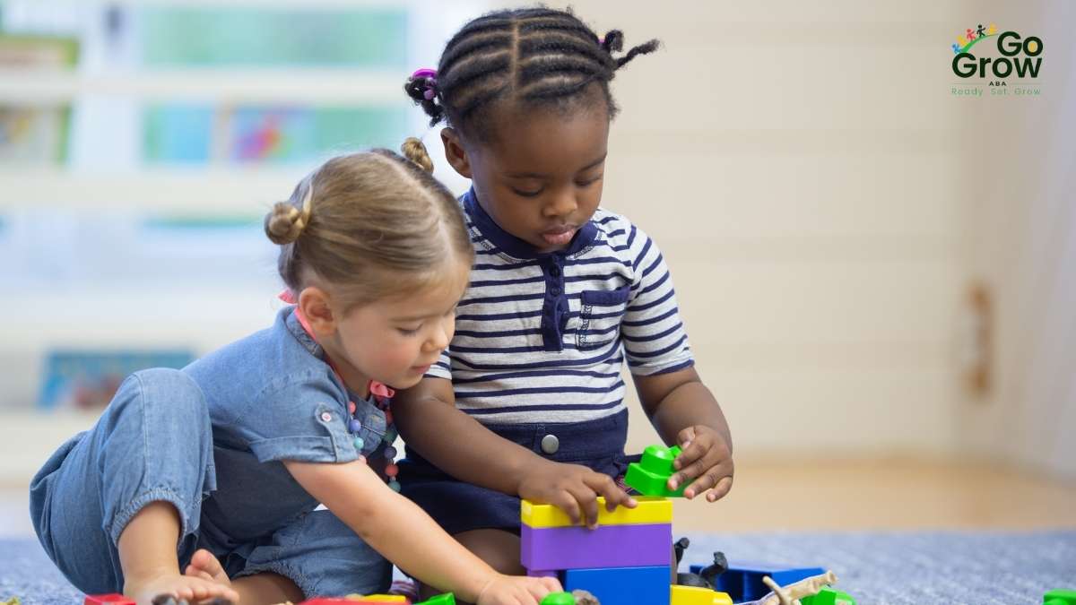 Two young children playing together with colorful building blocks on the floor