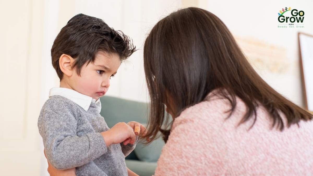 Young boy standing with a serious expression while talking to caregiver